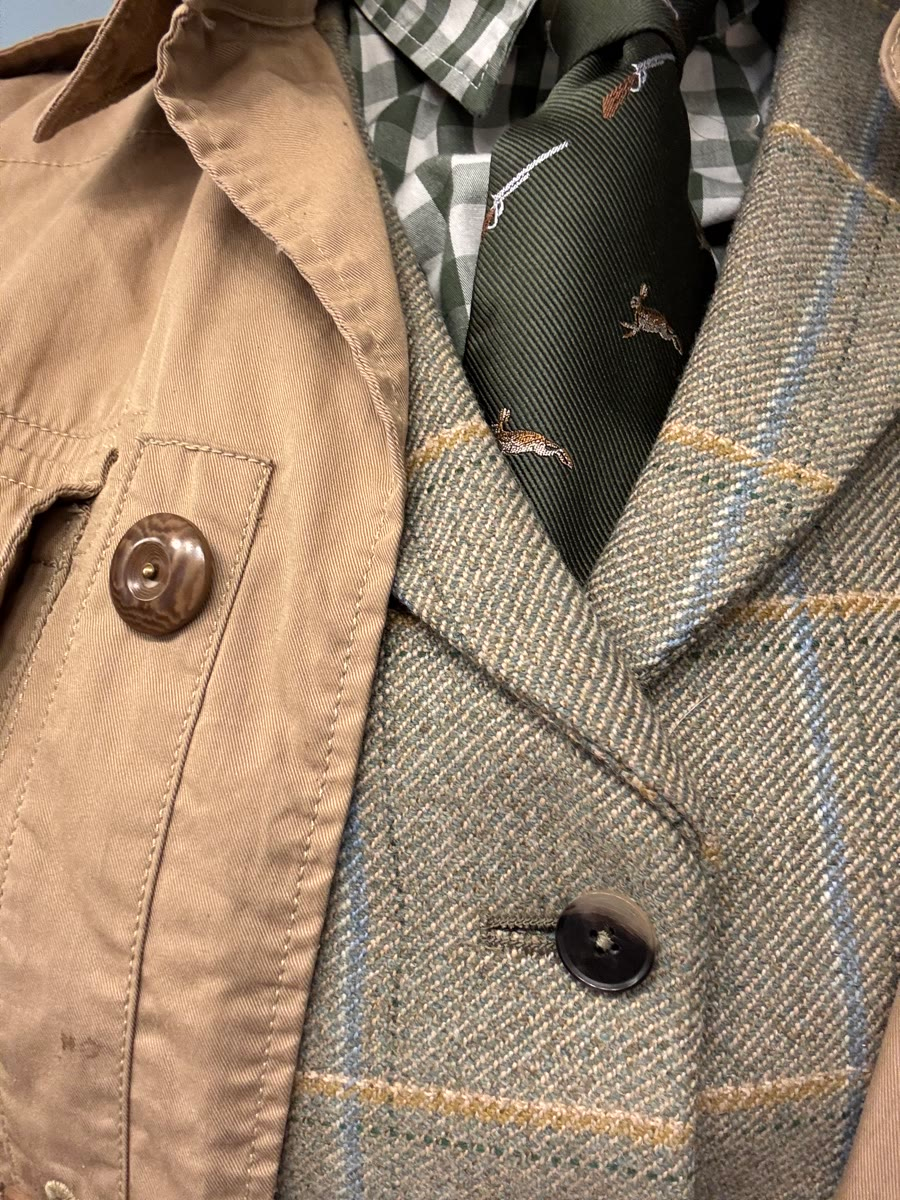Camel barn coat layered over a tweed vest and sporting tie
