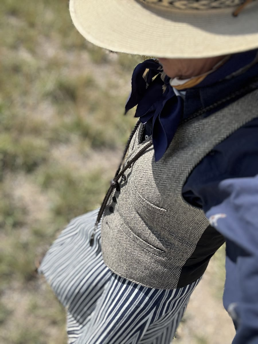 Pinstripe walking skirt with a herringbone vest and palm leaf hat